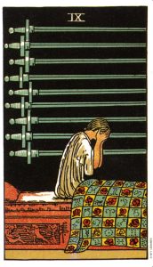 The nine of swords from the Pamela Coleman Smith-Waite deck. A person sits up in bed weeping into their hands while nine swords lie behind them horizontally filling the background.